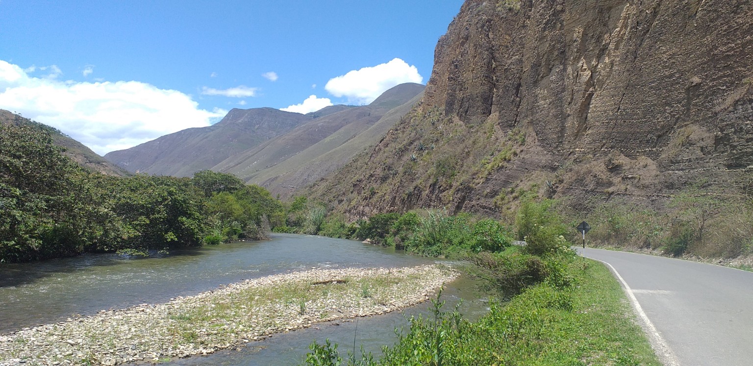 Carretera junto al río, rodeada de montañas en el valle